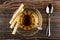 Wafer rolls and cup of tea on saucer, spoon on wooden table. Top view