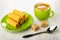 Wafer rolls in saucer, spoon, sugar, green cup with coffee on wooden table