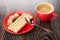 Wafer rolls, sugar on saucer, spoon, cup with coffee espresso on wooden table