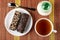 Wafers in chocolate with peanut on saucer, spoon, sugar bowl, cup of tea on mat. Top view