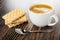 Wafers with, cup with black coffee, spoon on wooden table