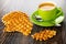 Wafers, pieces of wafer, cup with coffee espresso, spoon on saucer on wooden table