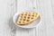 Wafers with powdered sugar covered with apple jam on a white plate on a wooden table