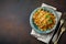 Wafers from zucchini with basil, parsley, sour cream and cheese in ceramic plate on dark concrete background. Selective focus