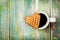 Waffle biscuits in shape of heart with cup of coffee on wooden background for Valentines day