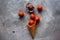 Waffle cone is filled with candies Halloween pumpkins on the grey background