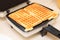 Waffle iron preparing waffles in kitchen