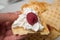 waffle in shaped heart with chantilly cream and raspberry in hand