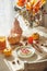 Waffles breakfast served on seasonal decorated autumn table with pumpkins, branch bouquet, autumn leaves and cutlery at window