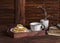 Waffles with honey and cream and tea with lemon in a vintage wooden tray on a dark wooden table. Books, glasses and vase with dry