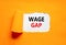 Wage gap symbol. Concept words Wage gap on beautiful white paper on a beautiful orange background. Business, support and wage gap