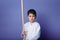 Waist length portrait of charming tranquil confident child boy aikido wrestler holding a wooden sword isolated on purple