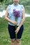 A waist portrait of a woman with a bouquet of wildflowers. Looks into the camera