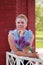 A waist portrait of a woman with a bouquet of wildflowers. In the park in a brick gazebo. Looks into the camera