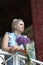 A waist portrait of a woman with a bouquet of wildflowers. In the park in a brick gazebo. Looks into the camera