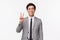 Waist-up portrait of cute cheerful asian male office worker, wear grey suit and tie, showing peace kawaii sign, beaming