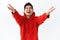 Waist-up portrait of dreamy happy young asian man, wearing red hoodie, raising hands and hold it up to catch something