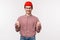 Waist-up portrait excited geeky young male in red beanie and glasses, pointing fingers down and smiling satisfied with