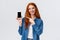 Waist-up portrait joyful charismatic redhead female review smartphone application, showing her photo with cute filter