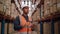 Waist up portrait of modern African American warehouse worker using digital tablet looking up at tall shelves in the