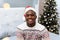 Waist up portrait of smiling African-American posing in cozy home interior, copy space. Cheerful handsome male in xmas