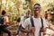 Waist up portrait of smiling millennial African American man hiking in a forest with friends, close up