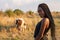 Waist up portrait of the toung african girl in black clothes stands among the field and looking at the camera over her