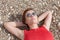 Waist-up portrait of woman lying on pebbles