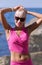 Waist up portrait of woman in pink top and skirt against rocky seashore