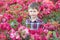 Waist up portrait of a young Caucasian boy in red roses bushes