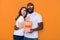 Waist up of scared interracial couple in white T-shirts posing for camera