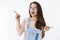 Waist-up shot of curious silly attractive european girl in glasses and overalls open mouth in excitement pointing