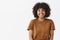 Waist-up shot of cute carefree friendly-looking African American teenage girl with afro hairstyle smiling broadly with