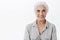 Waist-up shot of cute and kind wise elderly woman with white hair in casual shirt smiling broadly with assured and