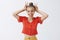 Waist-up shot of funny playful and childish attractive young woman with fair combed hair in vintage red blouse showing