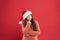 Wait a minute. Does Santa really exist. Winter traditions. Adorable girl with long curly hair wear santa claus hat red