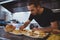 Waiter arranging food in plate at cafe