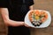 Waiter in a black apron holds dishes with sushi set in the shape of a heart for Valentine`s Day