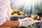 Waiter, carrying three plates with a rich salad at syny day