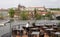 Waiter cleans tables at an outdoor restaurant on the riverbank of Vltava in Prague, with the Prague Castle in the background