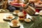 Waiter filling hot water into tea pot for customer with pice of cake on table.