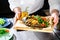 The waiter giving wooden board with delicious fish served with t