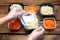 Waiter in gloves closing containers with salads at wooden table, closeup. Food delivery service