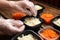 Waiter in gloves putting salads into containers at wooden table, closeup. Food delivery service