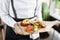 The waiter is holding a plate Roasted octopus BBQ with Baked potato. Restaurant menu