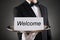 Waiter Holding Plate With Welcome Text On Paper