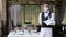 A waiter in a medical protective mask serves the table in the restaurant