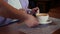 Waiter places a white cup of coffee on a napkin in front of the customer.