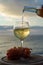 Waiter pouring aperitif white wine in glasses on outdoor tessace witn sea view