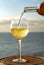 Waiter pouring aperitif white wine in glasses on outdoor tessace witn sea view